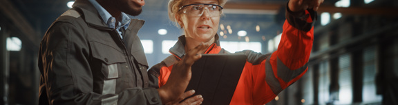 Surveying woman points to distant object while man looks at clipboard