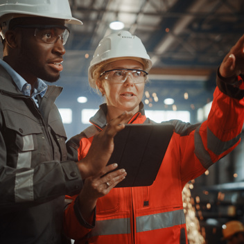 Surveying woman points to distant object while man looks at clipboard